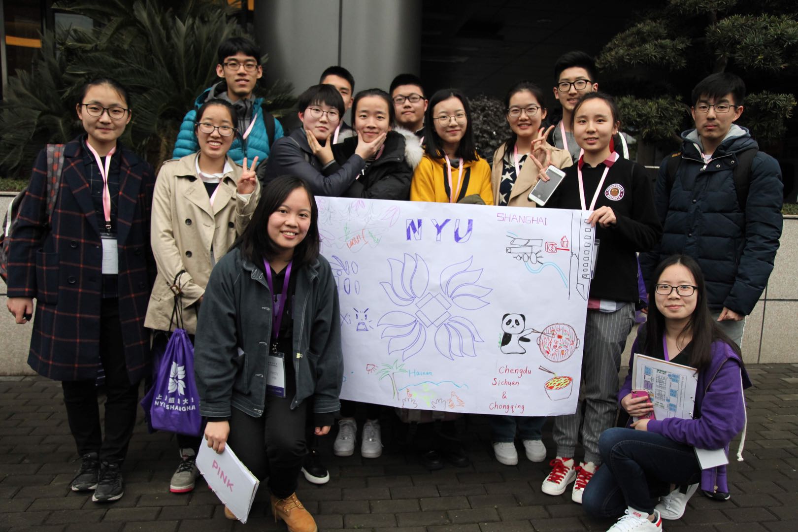 Students take group photo around poster