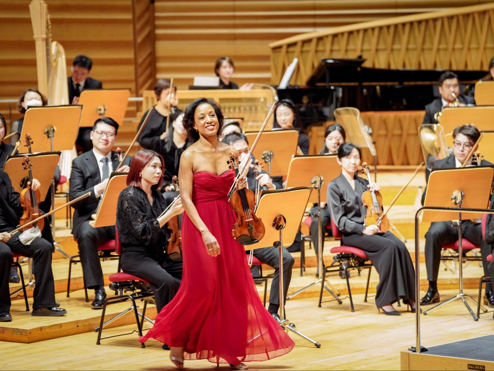 Violinst Kelly Hall-Tomkins walking on stage with the Shanghai symphony behind her. 