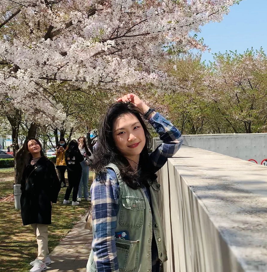 girl stands under blossoming cherry tree