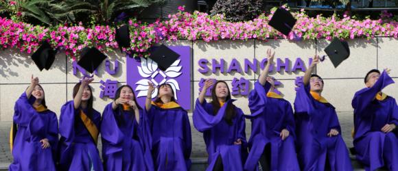 Students toss caps in front of NYUSH sign