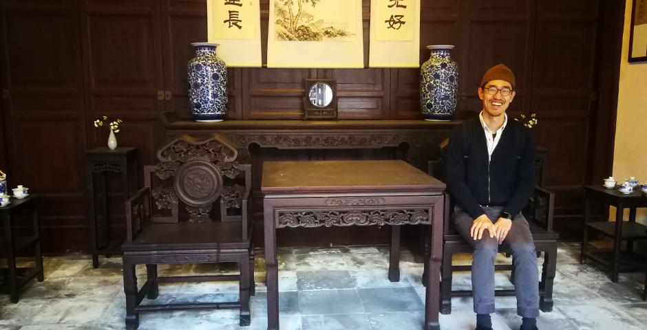 Vincent Qian from Community Engaged Learning tries out some of the furniture inside the Residence of Li.