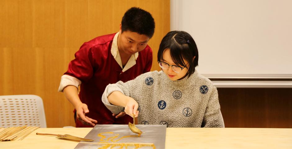 10月26日，两位中国传统艺术大师指导上纽大学生学习画糖画。用糖稀写字、作画，栩栩如生的动物跃然呈现，这就是民间工艺的艺术魅力。（摄影：胡文倩）