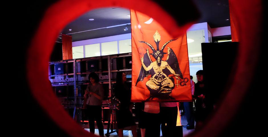 Immersed in playful hellfire, banners of demons and brains, and the heavy bass of a dark electronic soundtrack, audience members stand rapt before a giant screen depicting human creation via 3D printer and torturous visions of hell. (Photo by: NYU Shanghai)